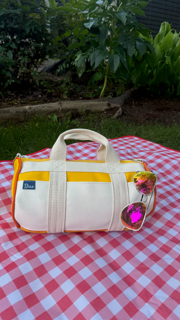 Sunburst barrel duffel on gingham picnic blanket with sunglasses, front view