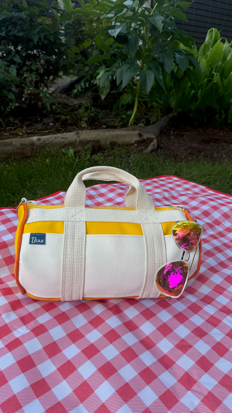 Sunburst barrel duffel on gingham picnic blanket with sunglasses, front view