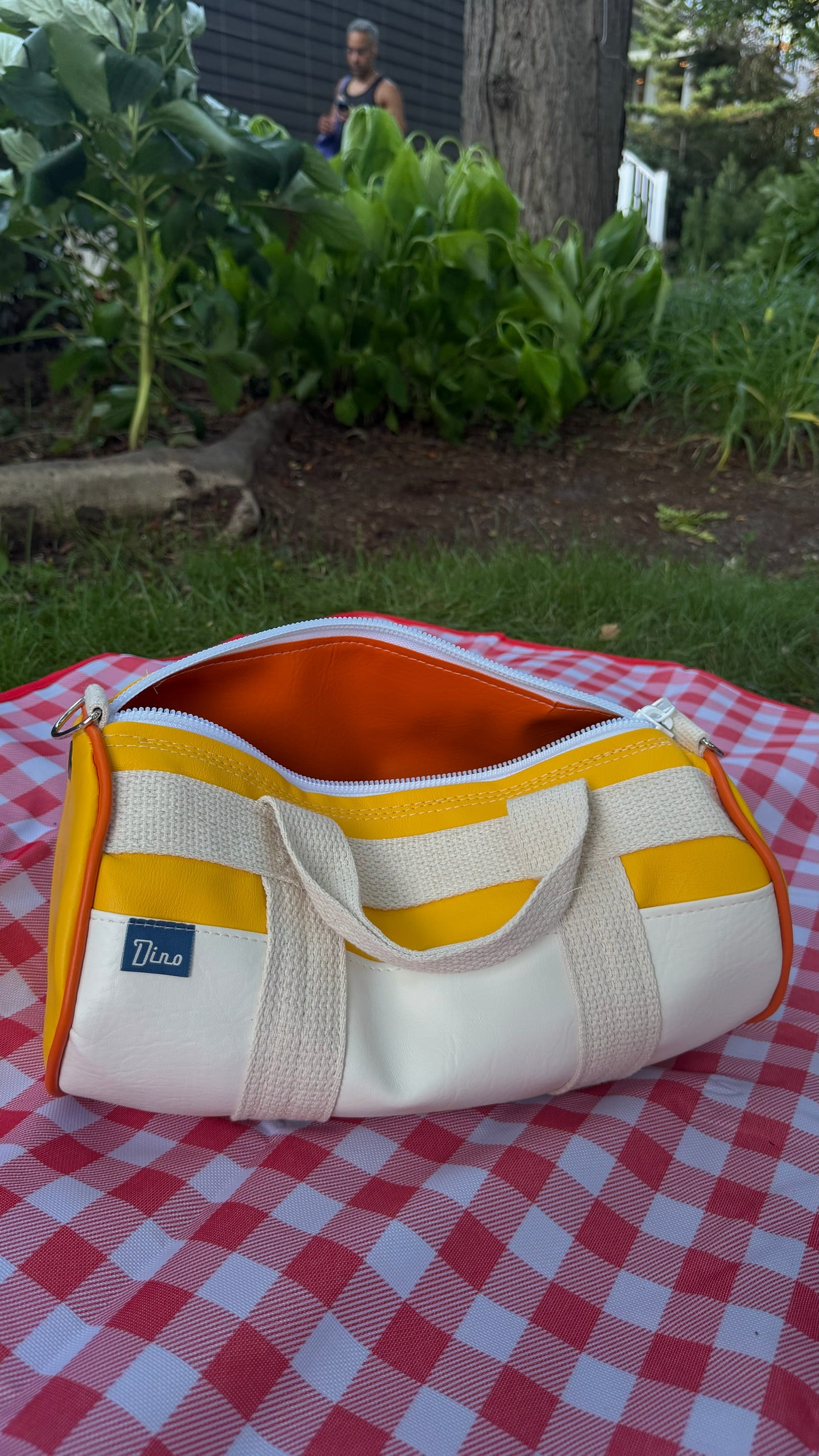 Sunburst barrel duffel open on gingham picnic blanket, top view
