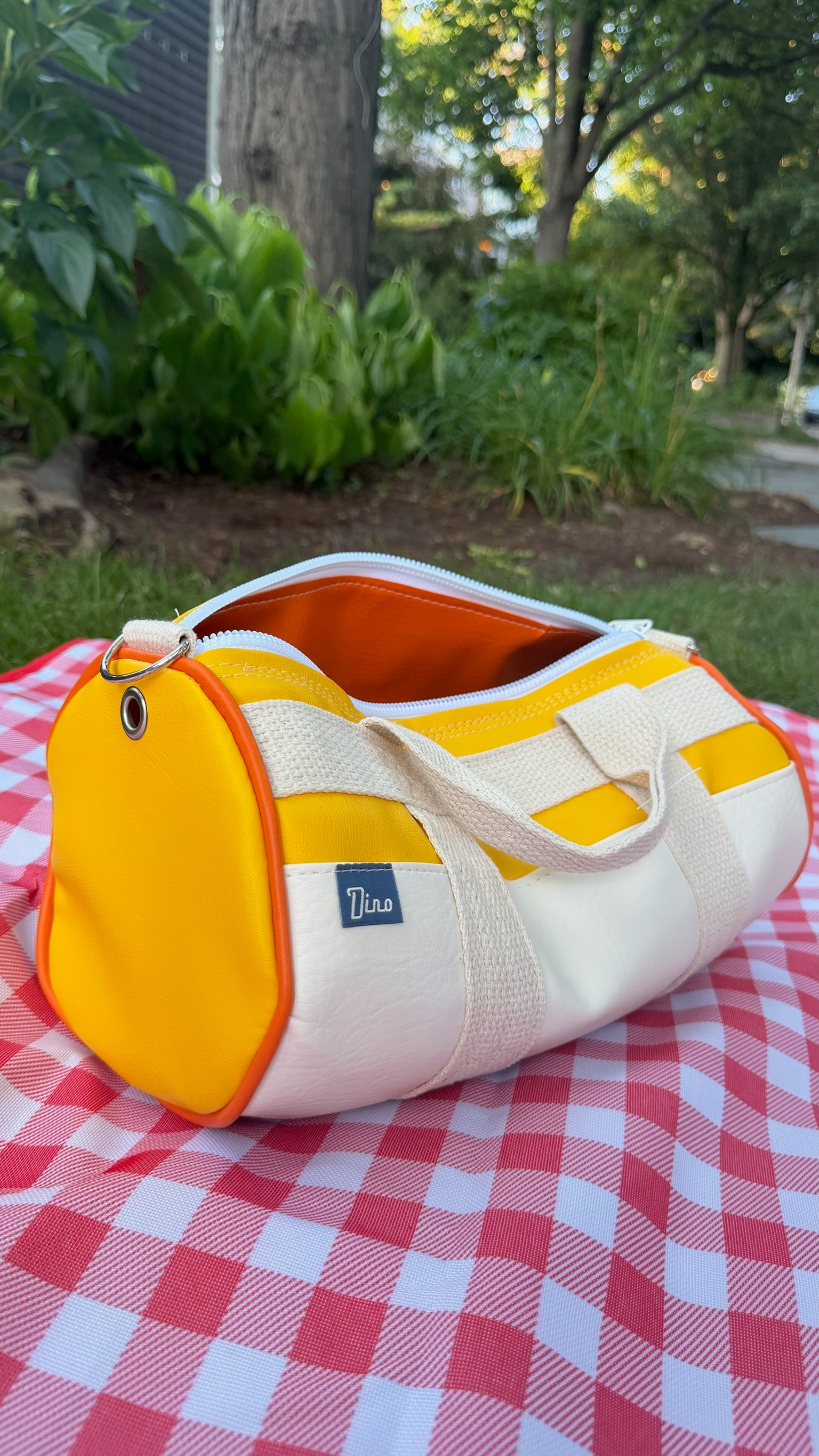 Sunburst barrel duffel open showing orange interior lining, side view